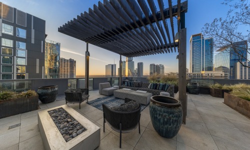 Luxury rooftop lounge with pergola seating, modern fire feature, and panoramic downtown skyline views at Sienna at The Thompson in Austin, Texas.